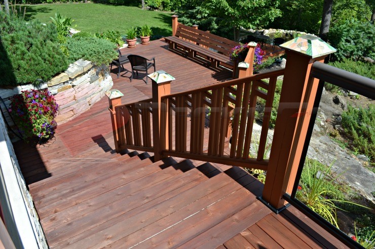 A top down view of stairs connecting a multi-level deck. This beautifully crafted deck features aluminum with glass panels and wood posts with 6x6 Titan Post Anchors™