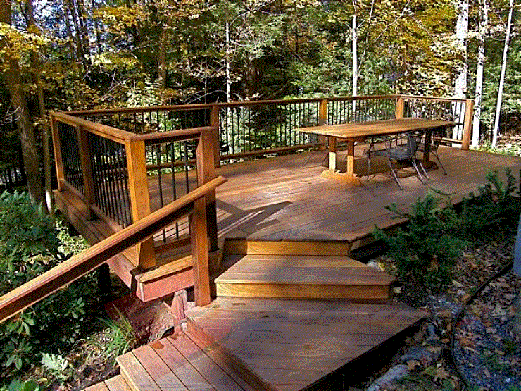 One With Nature This outdoor deck blends into its forest setting, looking like it naturally belongs. The dark earthy tones of the wood complements the trees and surrounding nature.